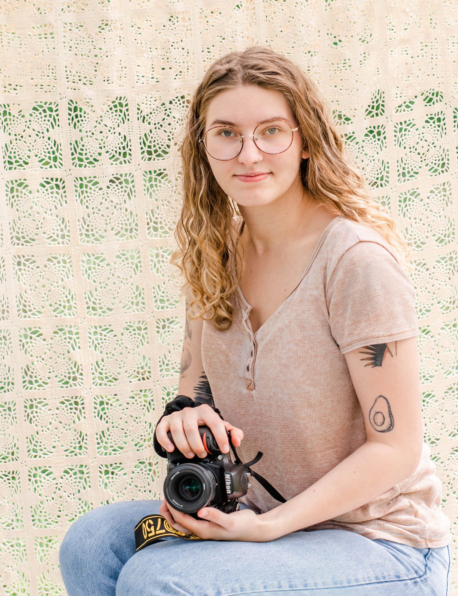 Creative portrait session with photographer holding camera against boho style backdrop outdoors.