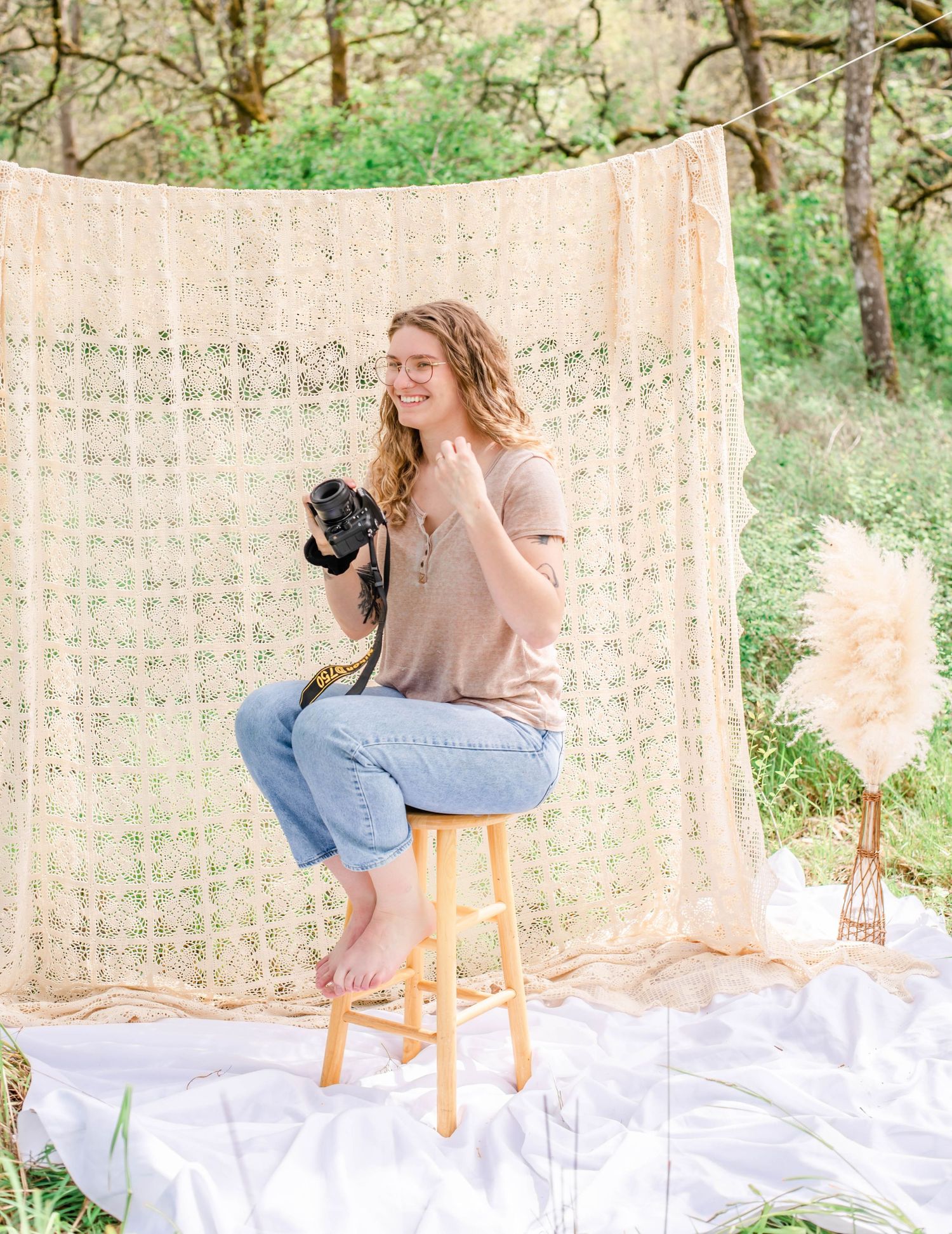 Natural light photography session with subject seated on wooden stool against woven backdrop.