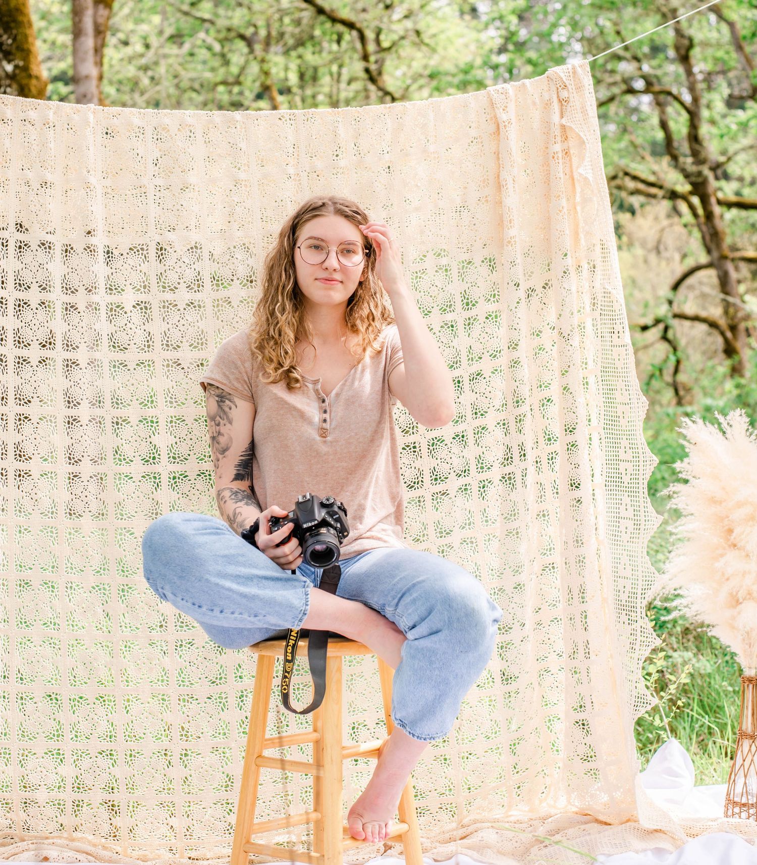 Relaxed portrait session with photographer holding camera against bohemian backdrop in nature.