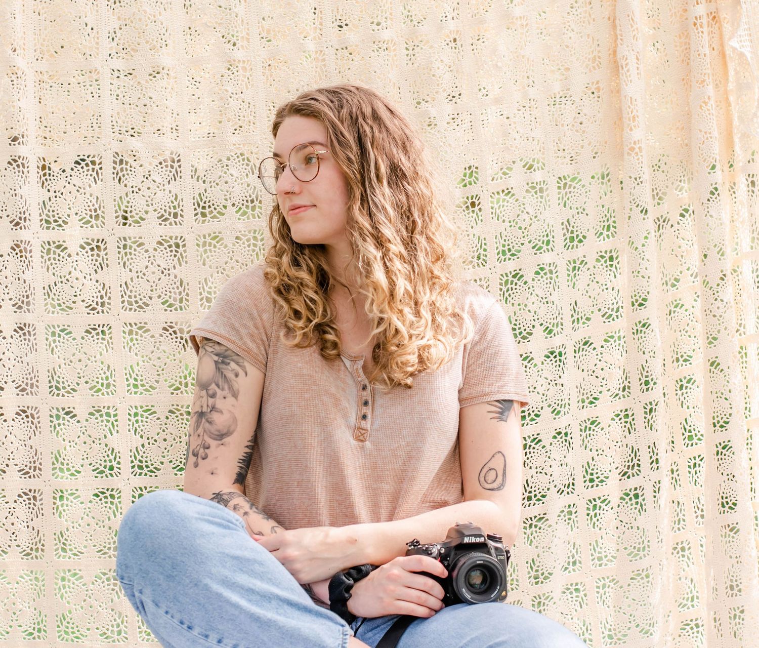 Creative portrait captures photographer with vintage camera against textured backdrop in natural setting.
