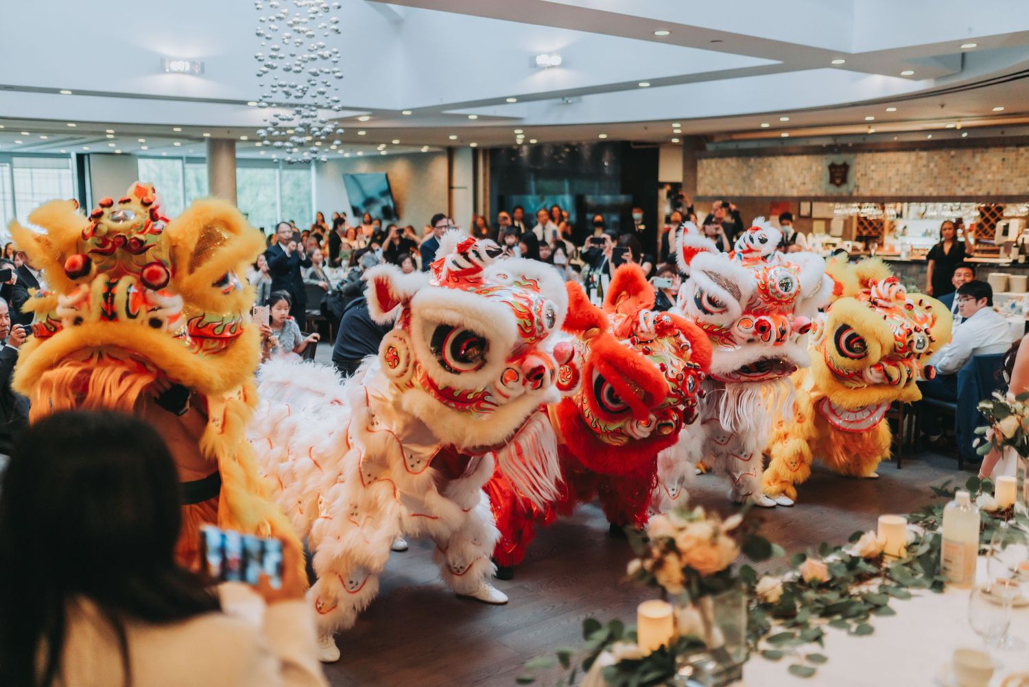 Traditional Chinese lion dance performers entertain wedding guests in a decorated banquet hall.