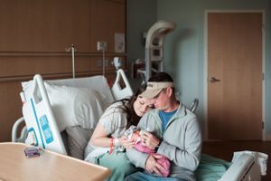 New parents share a tender moment with their newborn baby in a hospital room.