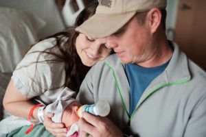 Parents cradle and bond with their newborn baby in a hospital bed.