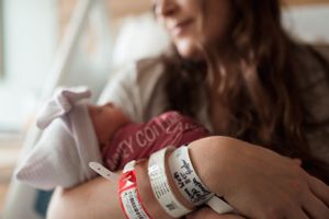 Hospital identification bracelets shown on wrist during newborn care.