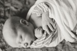 Close-up view of a sleeping newborn wrapped in white hospital blankets.
