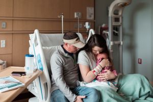 Family shares emotional first moments with newborn in hospital room.
