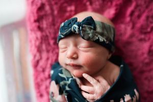 Close-up portraits of a sleeping newborn baby with a floral headband.