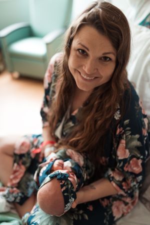 Woman in floral dress smiling while looking down at something off camera.