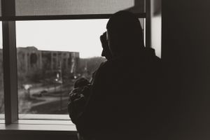 Silhouetted figures by large windows in a modern room.