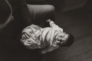 Black and white photo of sleeping infant wrapped in white clothing on dark surface.