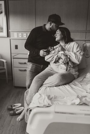 Black and white hospital photo capturing intimate family moment with newborn.