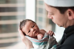 A tender moment captured between parent and newborn baby in soft natural light by a window.