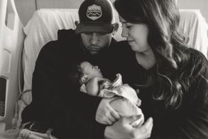 Black and white portrait of parents admiring their sleeping newborn.