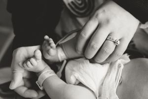 Tender moment of hands gently cradling a sleeping newborn.