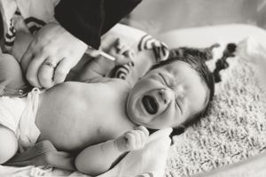 Black and white image of a baby lying on textured blanket.