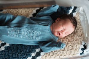 Baby resting on carpet with soft window light streaming in.
