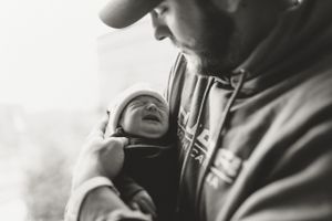 Black and white close-up photo of a newborn baby being held during a lifestyle photography session.