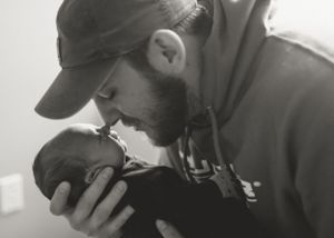 Intimate black and white photo of parent holding sleeping newborn baby during lifestyle session.