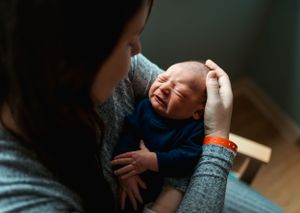 Tender moment captured between parent and newborn baby in natural window light.
