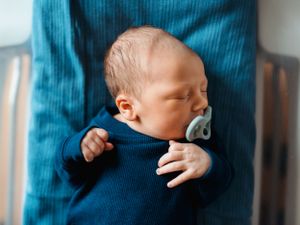 Newborn wearing blue outfit during candid lifestyle photography session.