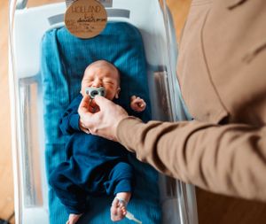 Lifestyle photo of baby in blue outfit on changing table during newborn session.
