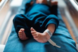 Baby in blue outfit lying on changing table during candid lifestyle photography.