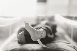 Close-up of tiny newborn baby toes and fingers against a soft gray blanket.