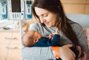 Intimate family moment with newborn baby being cradled in a cozy home setting.