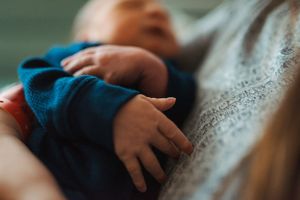 Tiny newborn hands and feet against a blue and gray background.