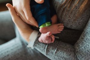 Close-up details of newborn baby features with soft gray textile.