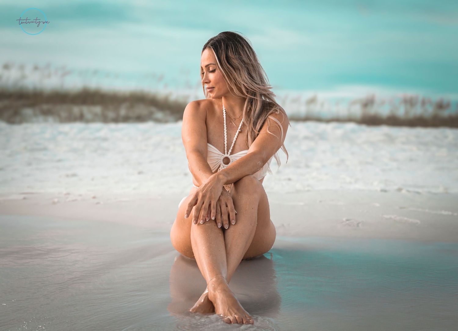 A tranquil beach scene with a contemplative figure sitting in the sand during a dreamy tropical sunset.