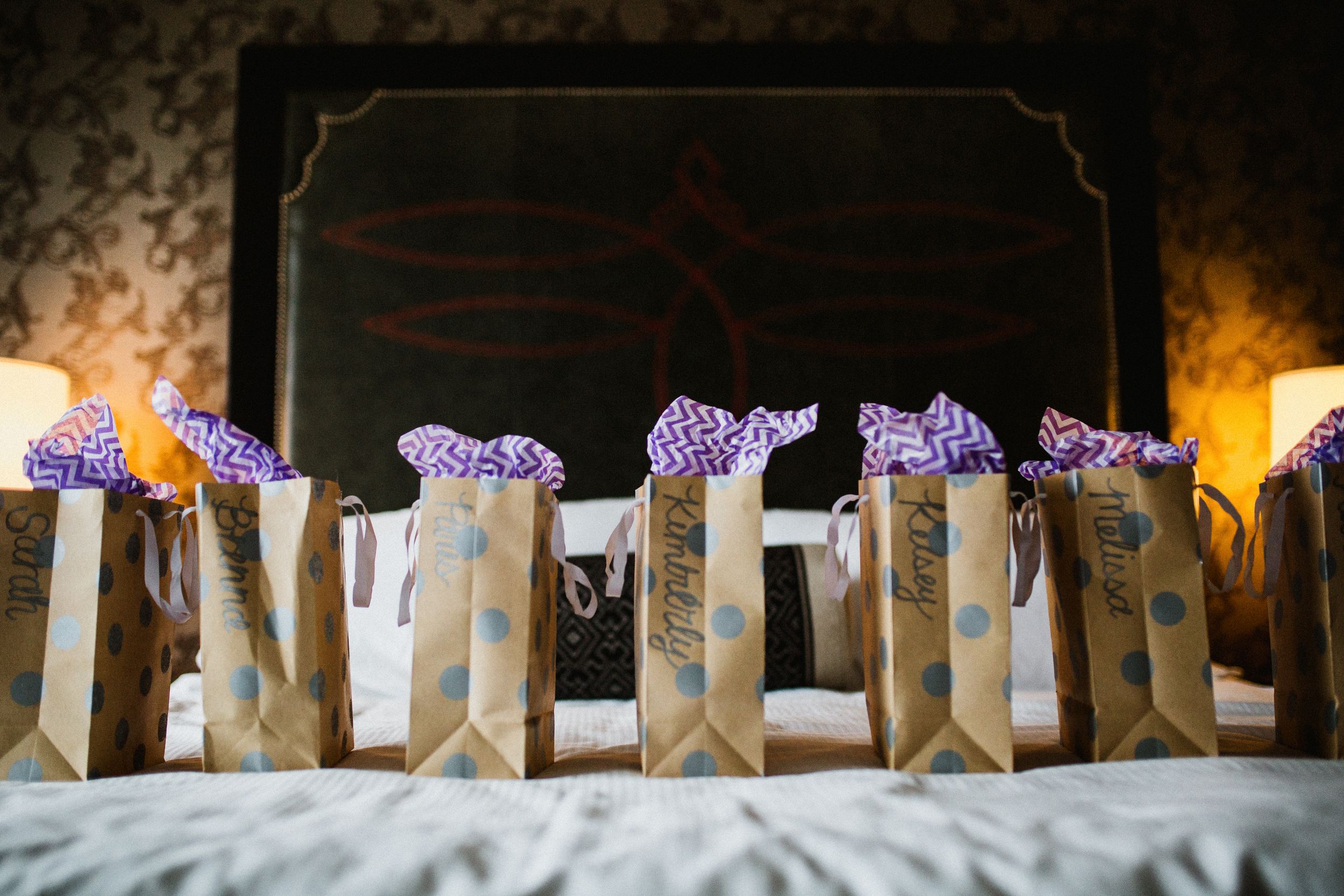 Brown paper favor bags decorated with purple bows lined up on a display.