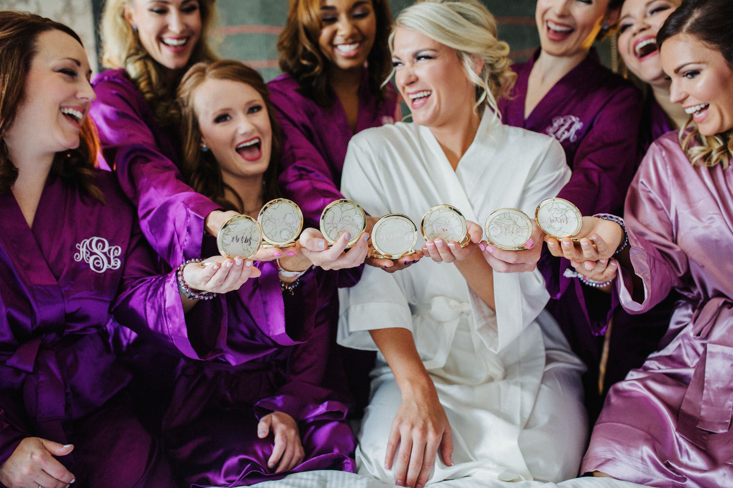 Wedding party wearing purple robes laughing together during pre-ceremony getting ready moments.