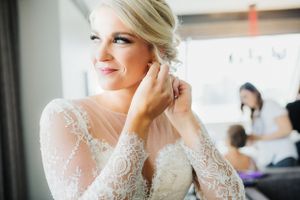 Elegant lace wedding dress detail with intricate beading against a bright window.