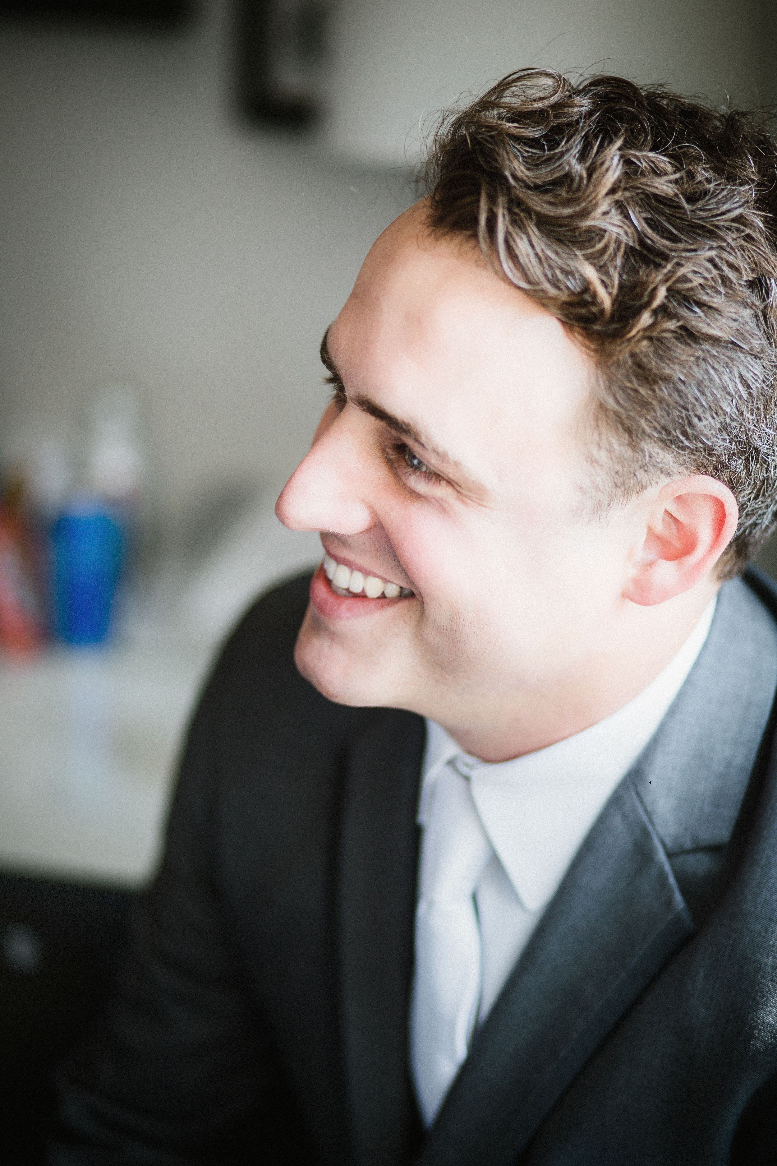 Profile portrait showing genuine joy and laughter in formal attire.