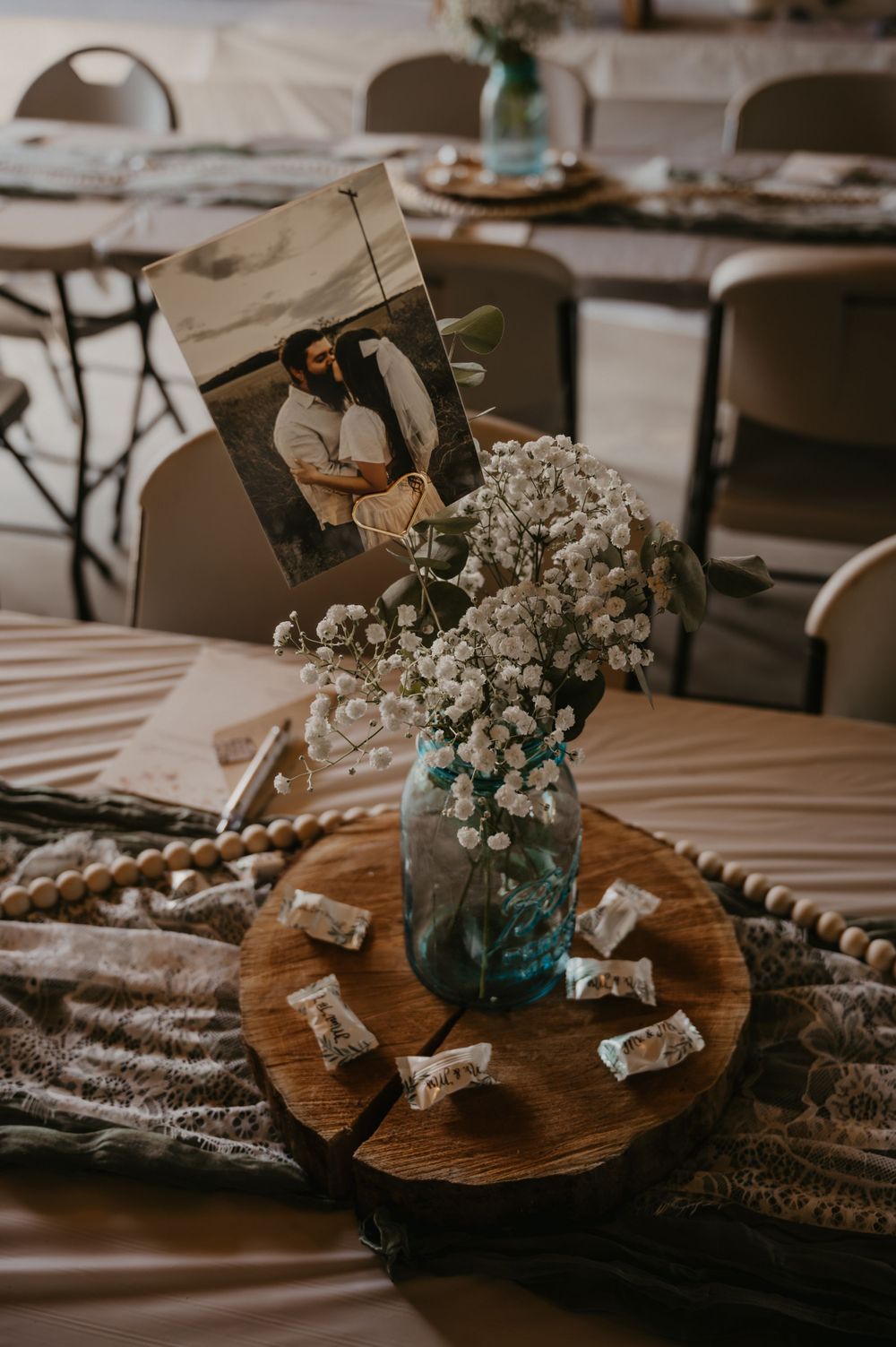 Rustic bridal shower centerpiece with baby's breath in blue mason jar and couple's photo.