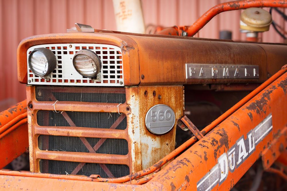 Close-up view of vintage orange tractor grills and headlights showing rustic patina and weathered details.
