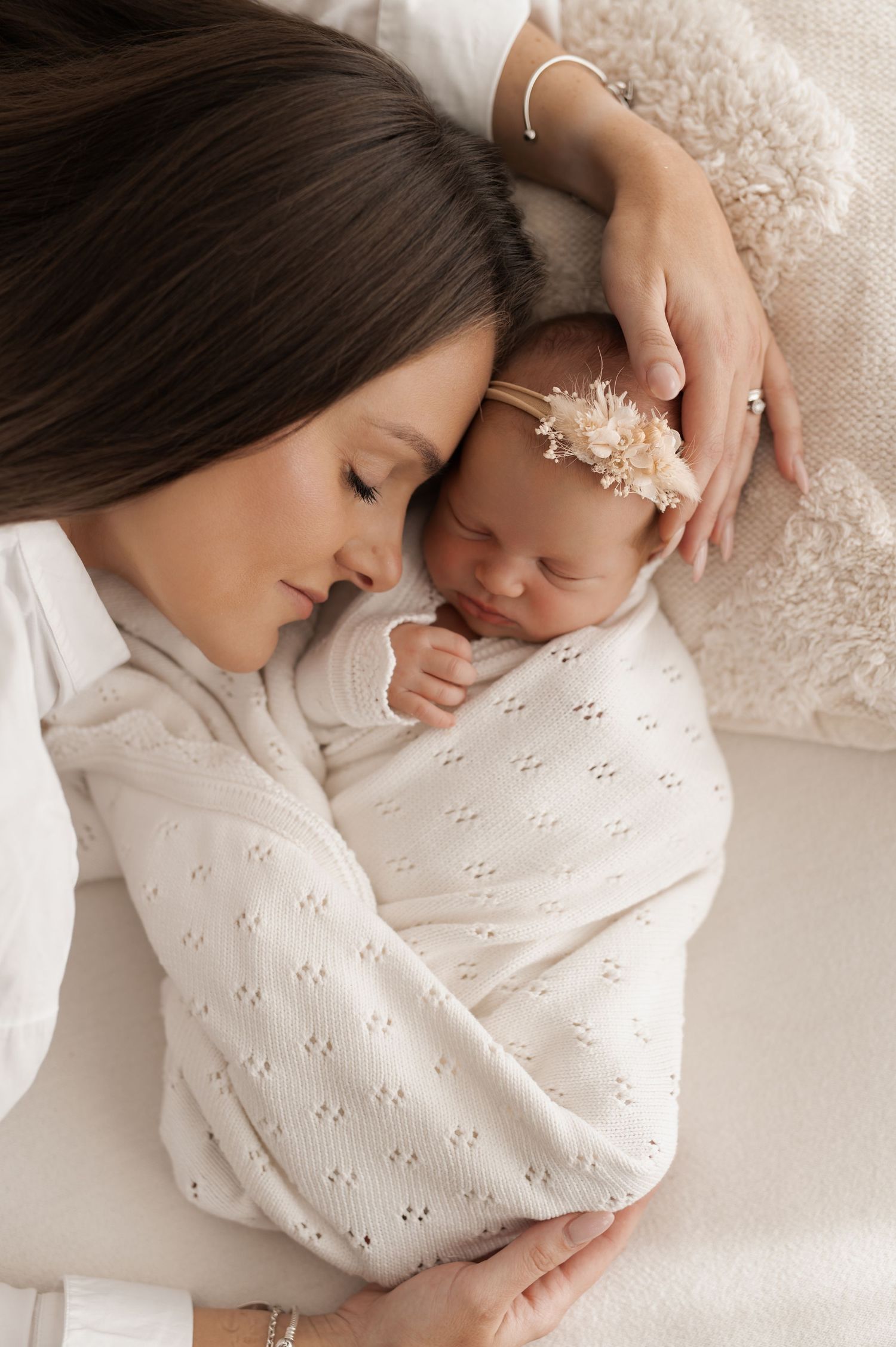 Intimate family portrait with newborn baby in soft white studio setting.