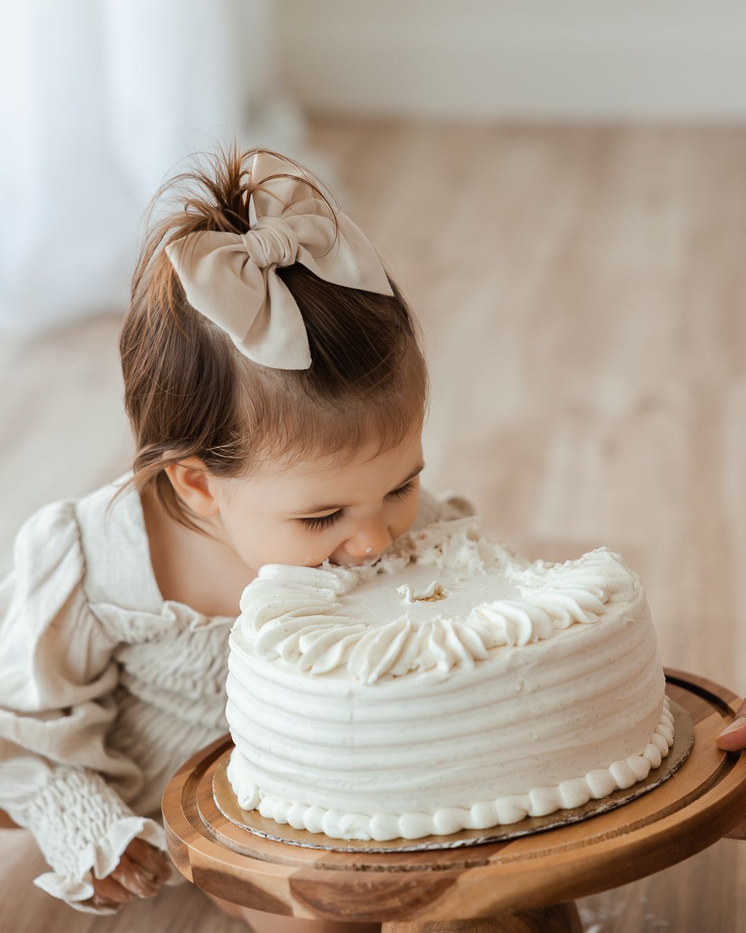 A series of girlish side profile shots as she tastes a white cake from a rustic wooden platter.