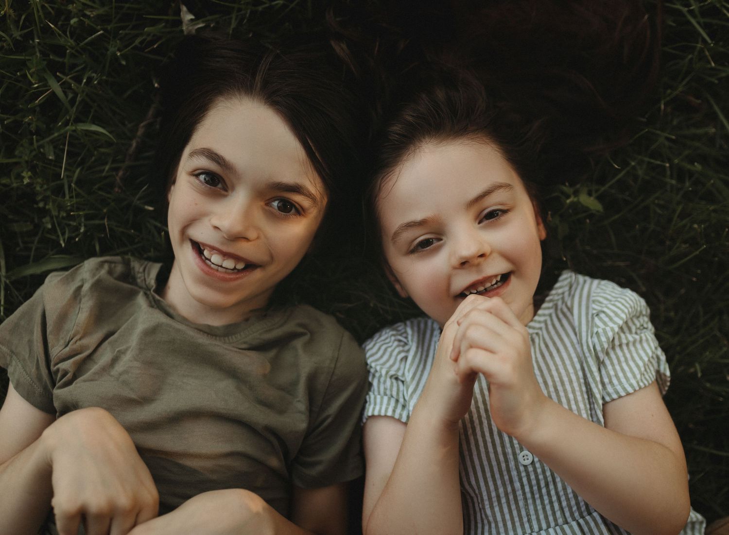 siblings laughing in the grass – candid and playful childhood photography in Kansas