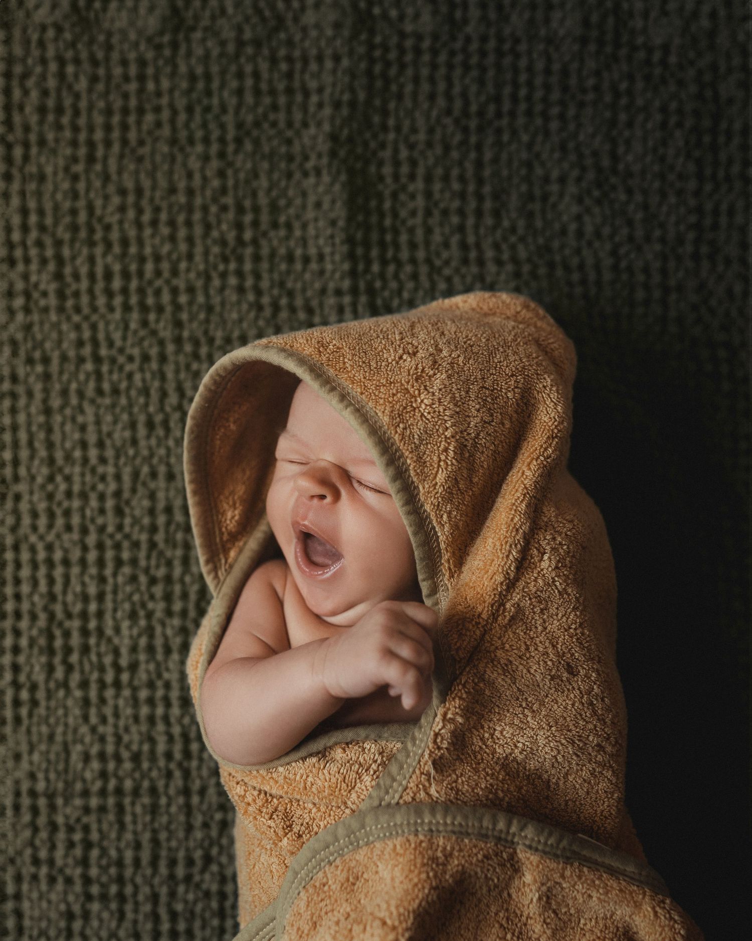 Yawning newborn wrapped in cozy towel – natural and intimate baby photography