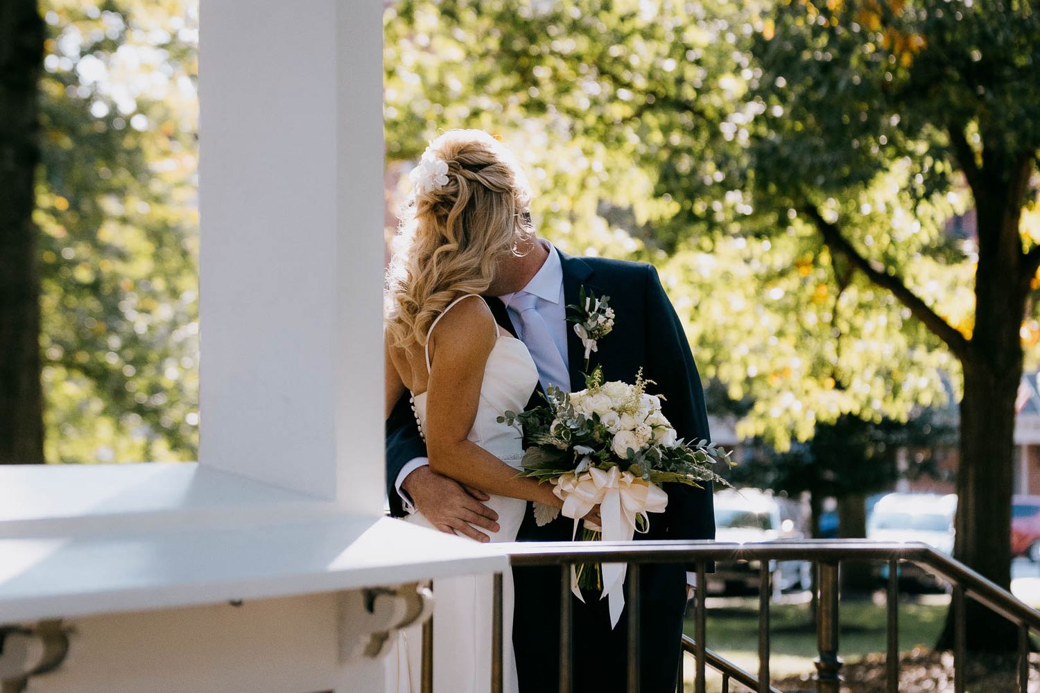 Couple share a romantic kiss under a white gazebo during the natural light portraits captured by Cleveland wedding photographer.