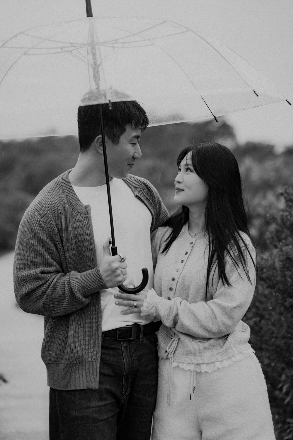 A romantic couple shares tender moments under an umbrella in a series of black and white photographs.