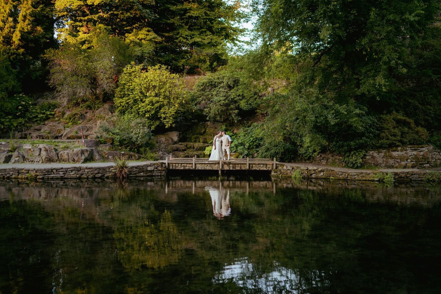 Bride and groom sharing a romantic moment on a dock surrounded by lush greenery of PNW and a calm reflective lake.