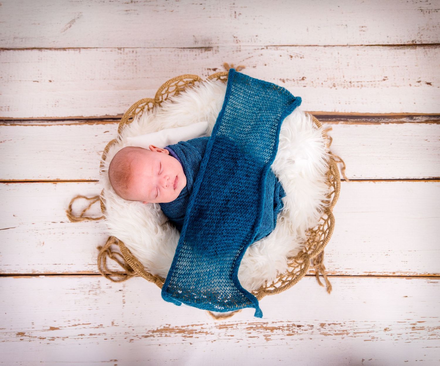 Teal blue denim fabric swatches arranged with twisted rope against white wooden planks background.