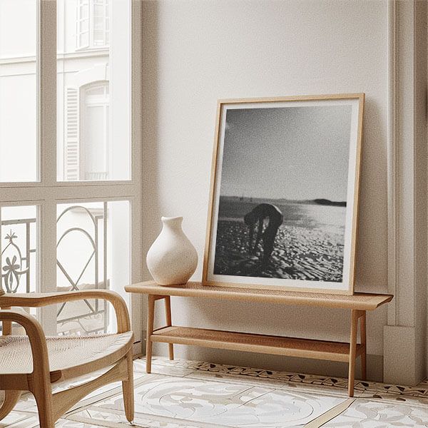 Modern interior with wooden bench and framed black and white photograph next to window.