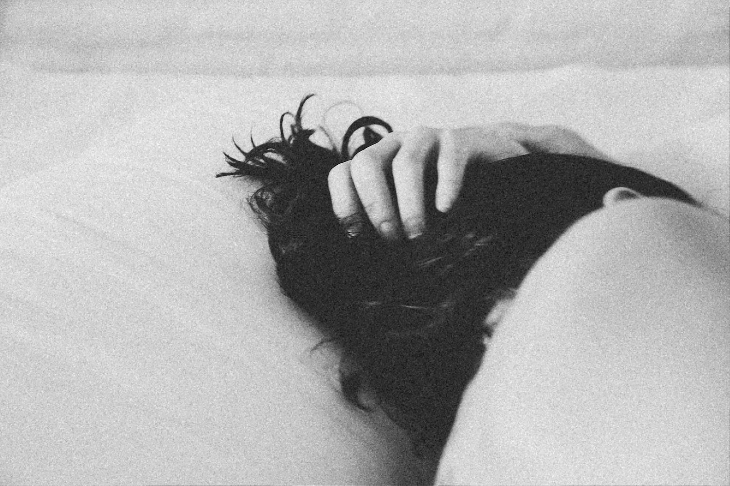 Close-up black and white photo of fingers running through dark hair.