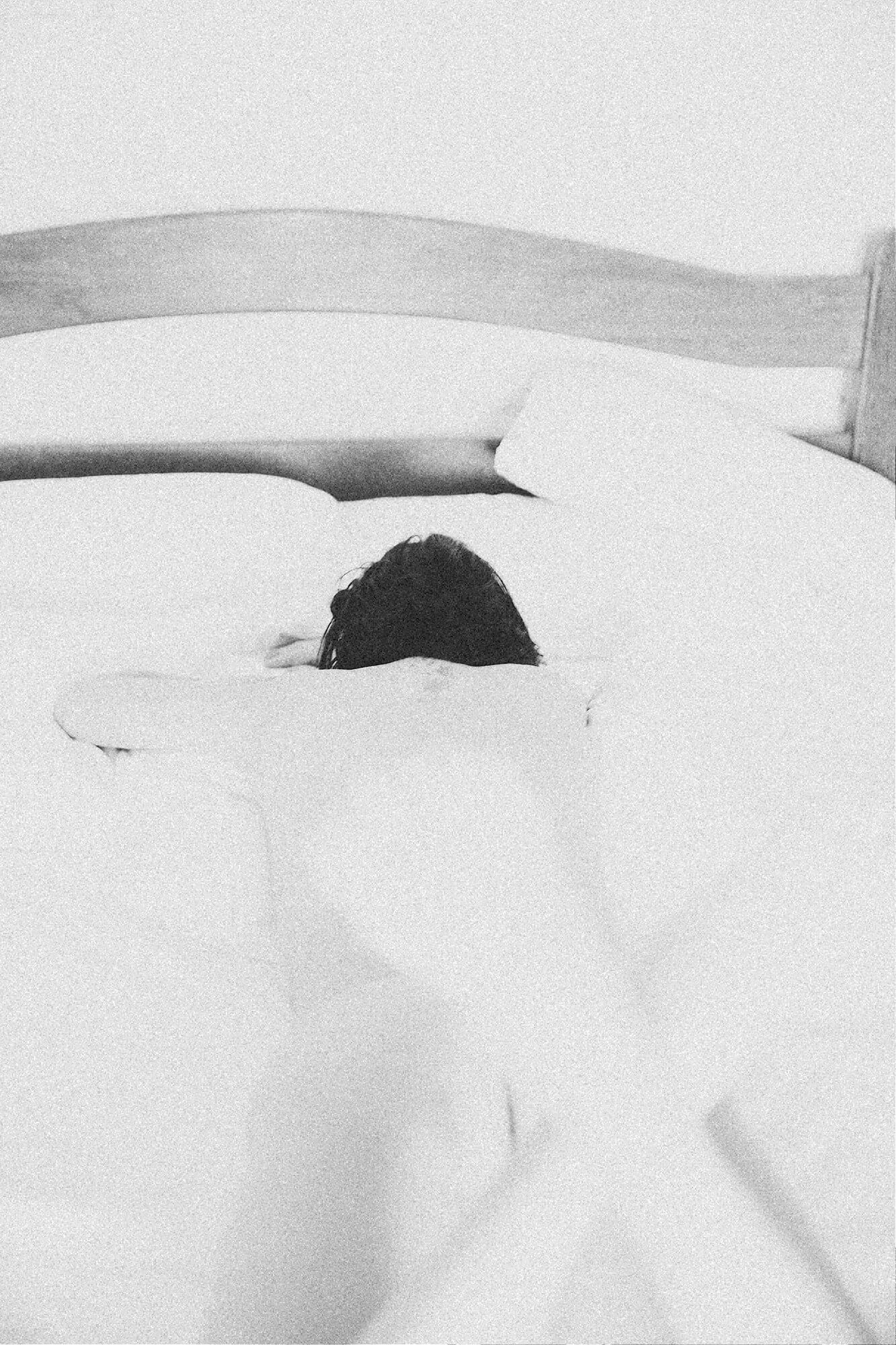 Minimalist black and white photo of sheets and pillows on a bed.