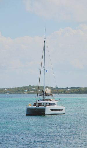 Luxury catamaran sailboat anchored in crystal clear turquoise tropical waters.