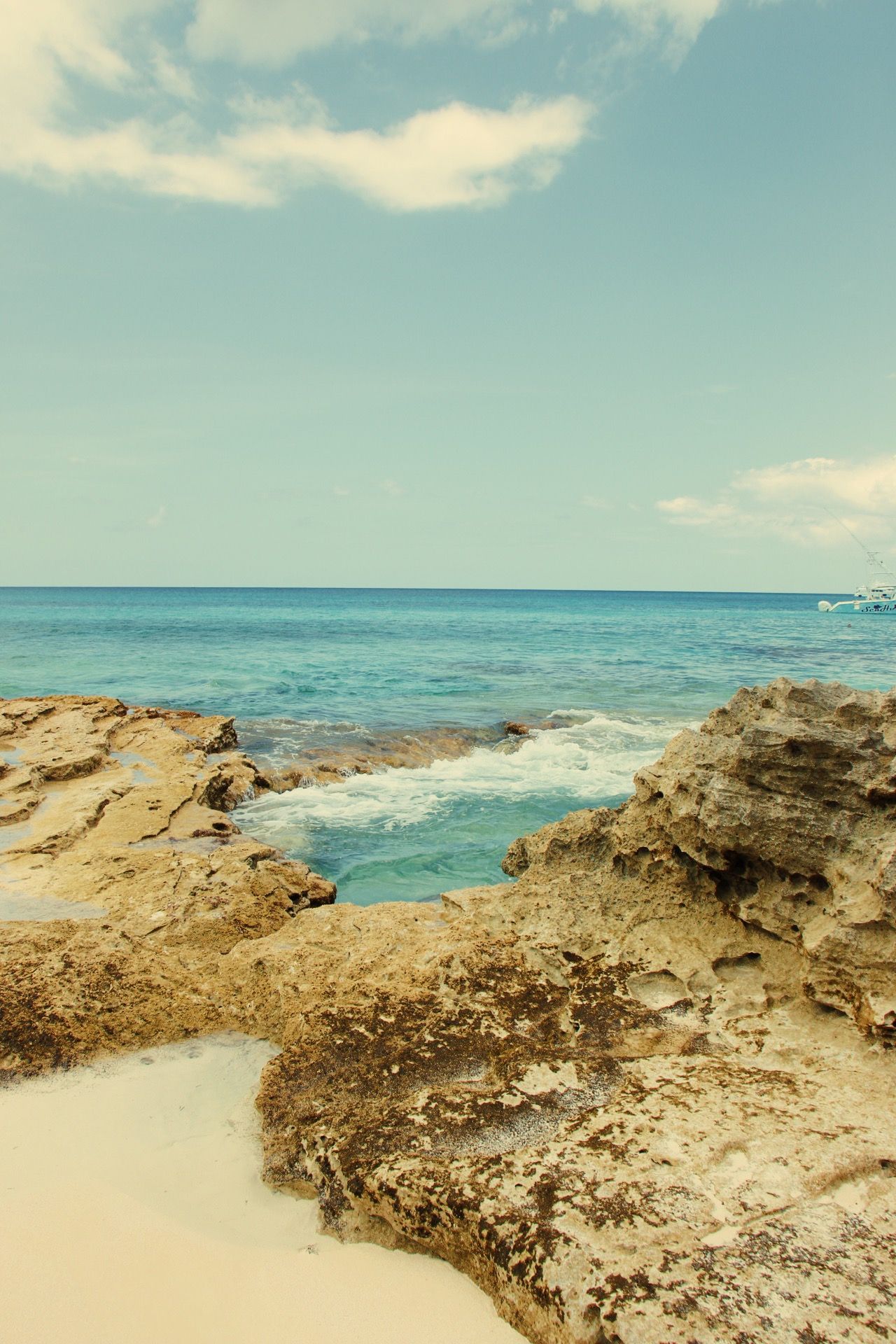Rocky coastal formations frame crystal clear turquoise waters under bright sky.